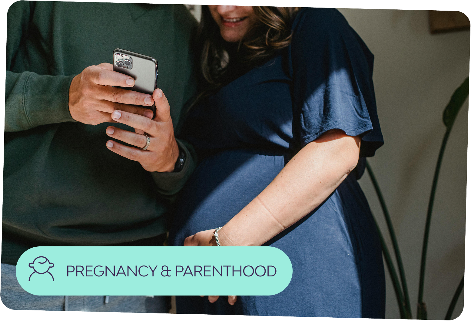 Closeup of a pregnant person and their partner looking ath the Peppy app on a phone