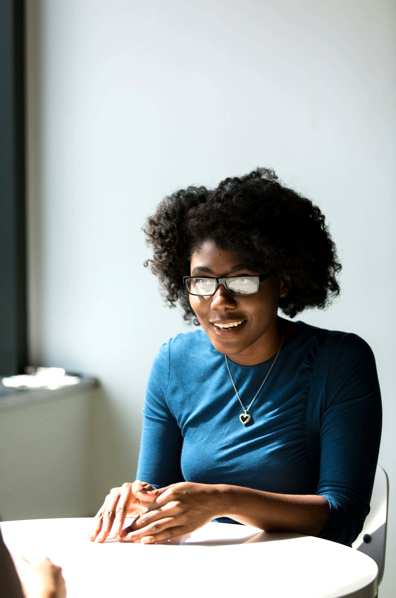 Close up of a woman sitting at a table chatting to a colleague in the foreground