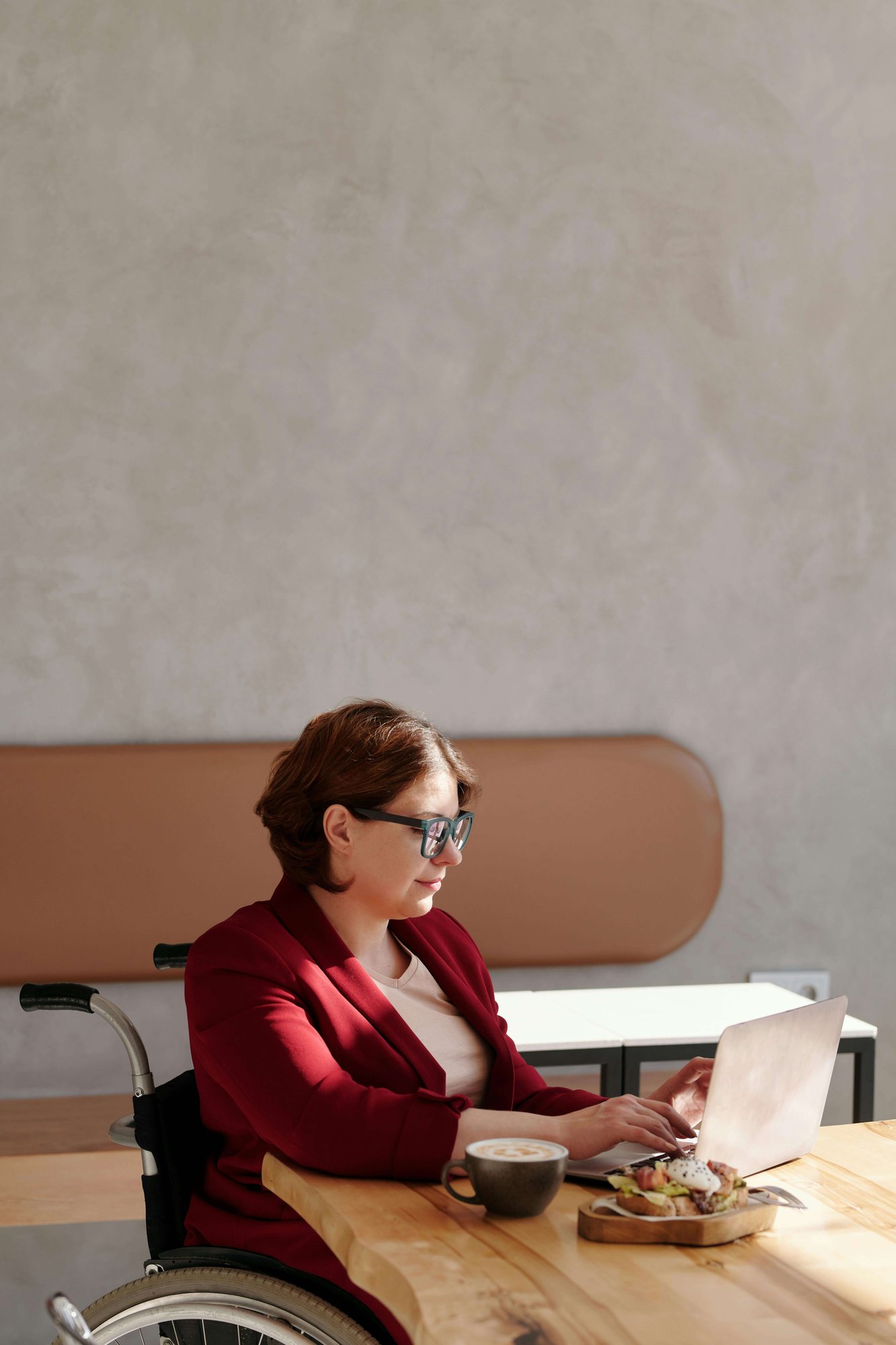 HR professional in a wheelchair working on a laptop, supporting her team’s wellbeing
