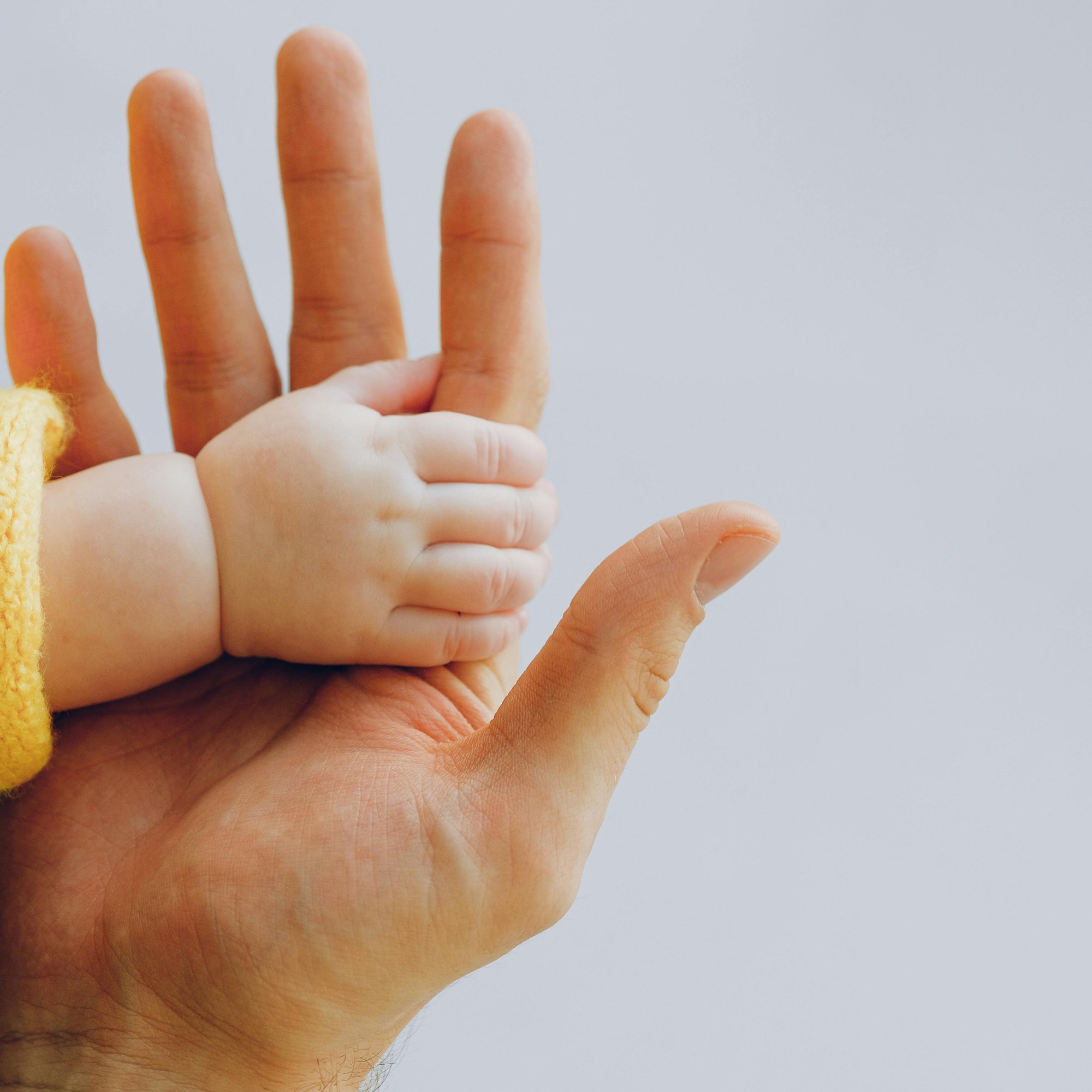 a baby's hand holding on to an adult hand