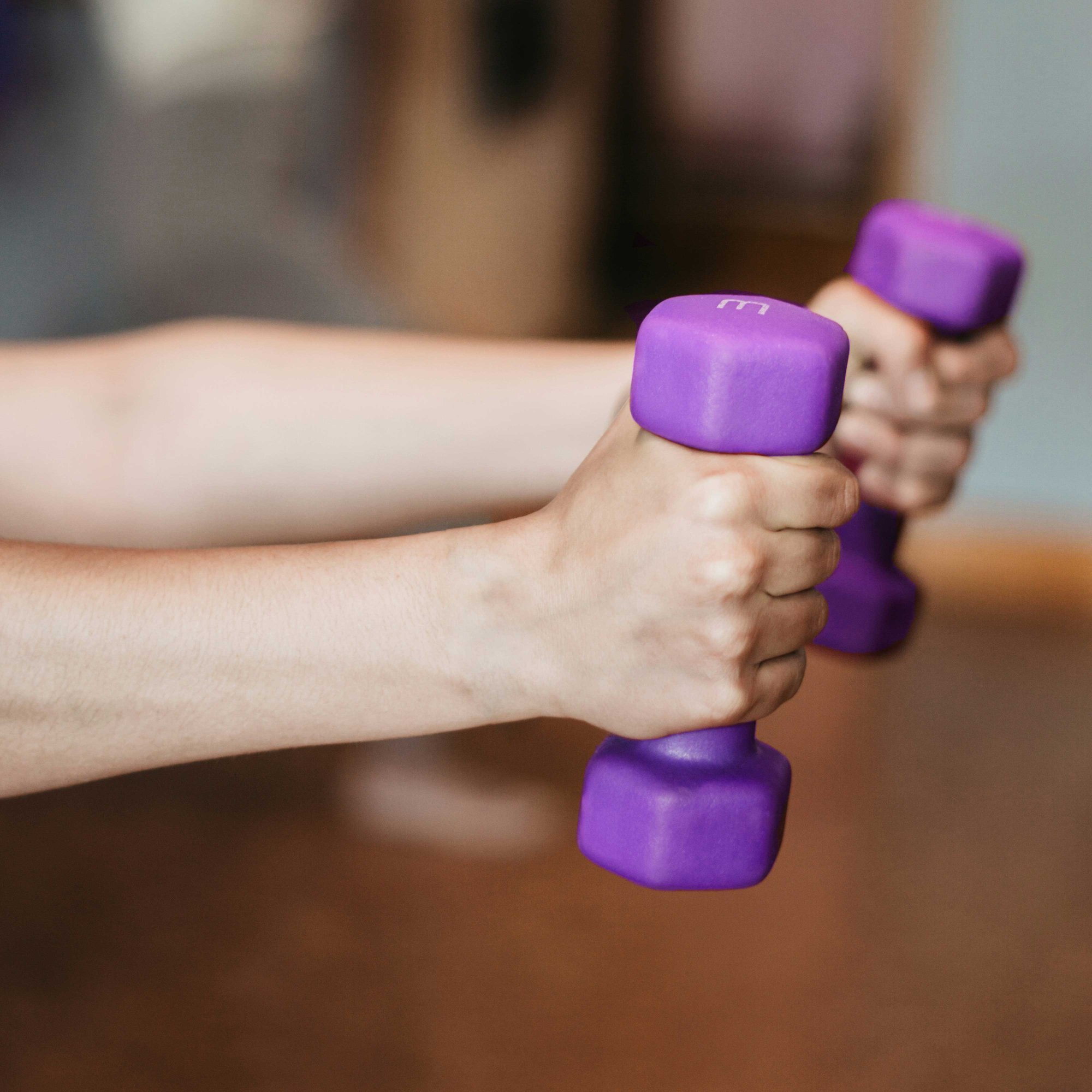 a close-up of hands holding purple coloured dumbbells